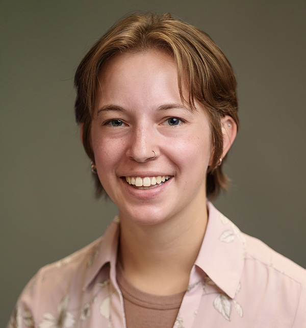 Headshot of Alyssa smiling and wearing a pink collared shirt in front of a neutral background.