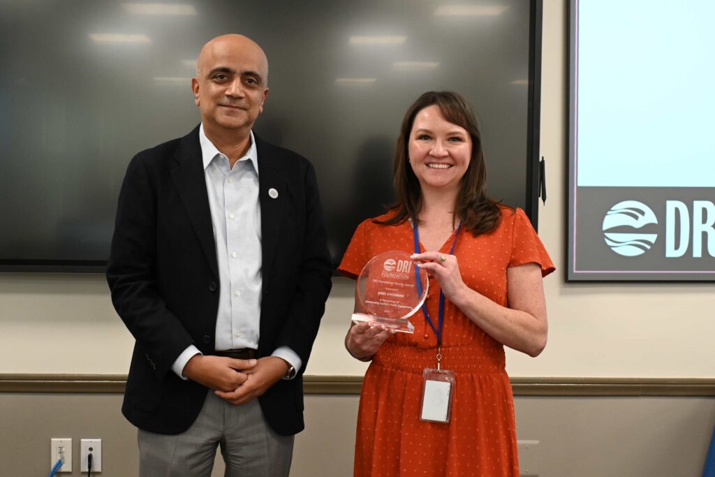 A man standing next to a woman in a red dress holding an award.