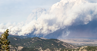 Wildfire smoke and ash plume on a mountain top.