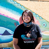 Autumn Harry smiling and standing in front of a mural of Pyramid Lake. 