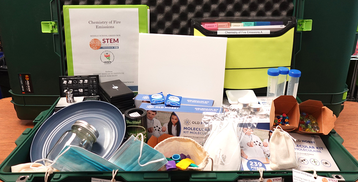An open Green Box displaying STEM materials for the Chemistry of Fire Emissions.