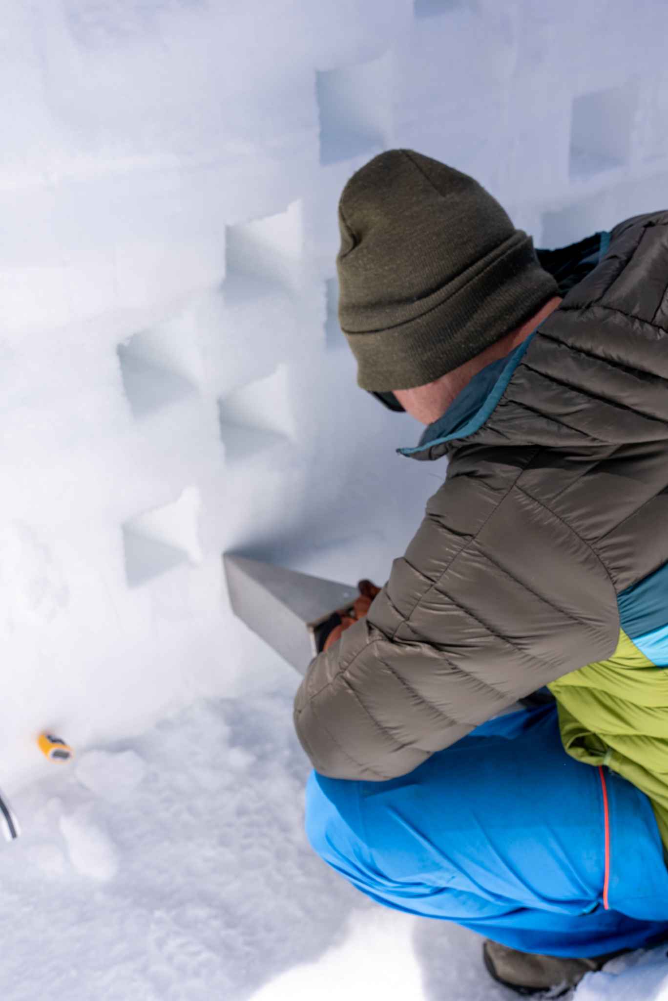 Researcher taking a snow sample from a wall of snow.