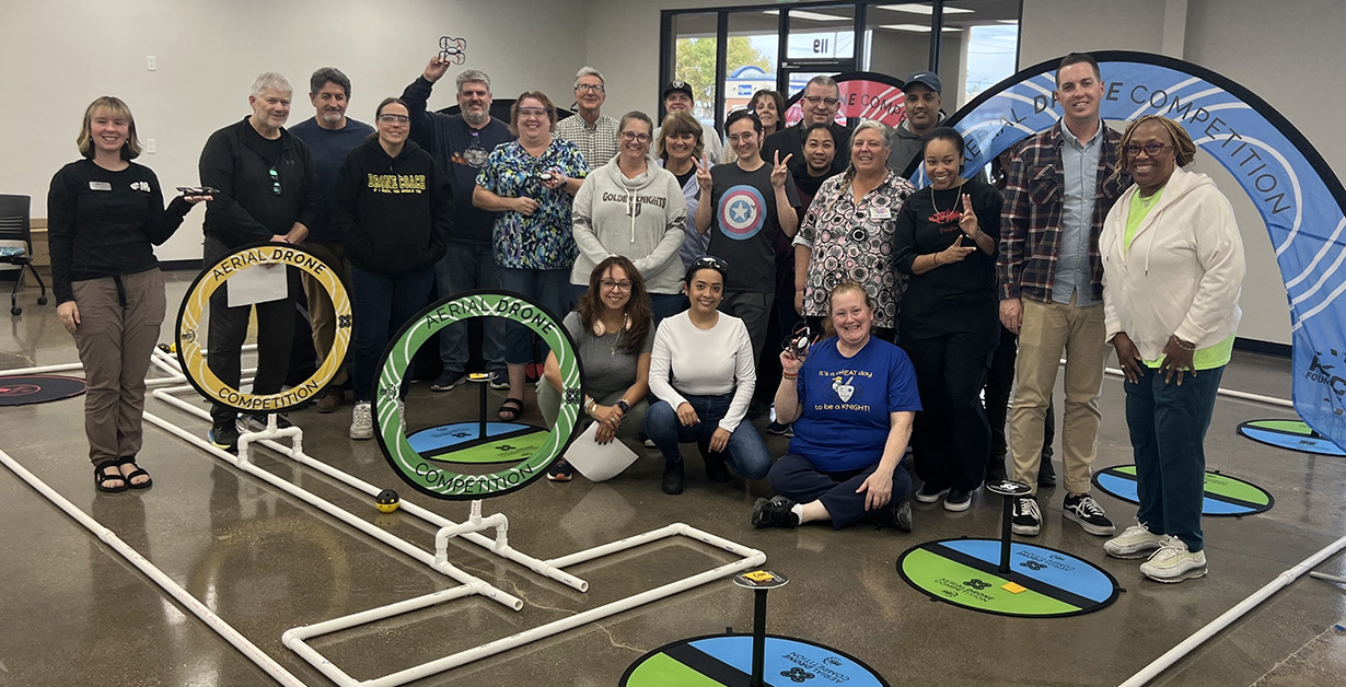 Group of educators posing for the camera on a drone obstacle course. 