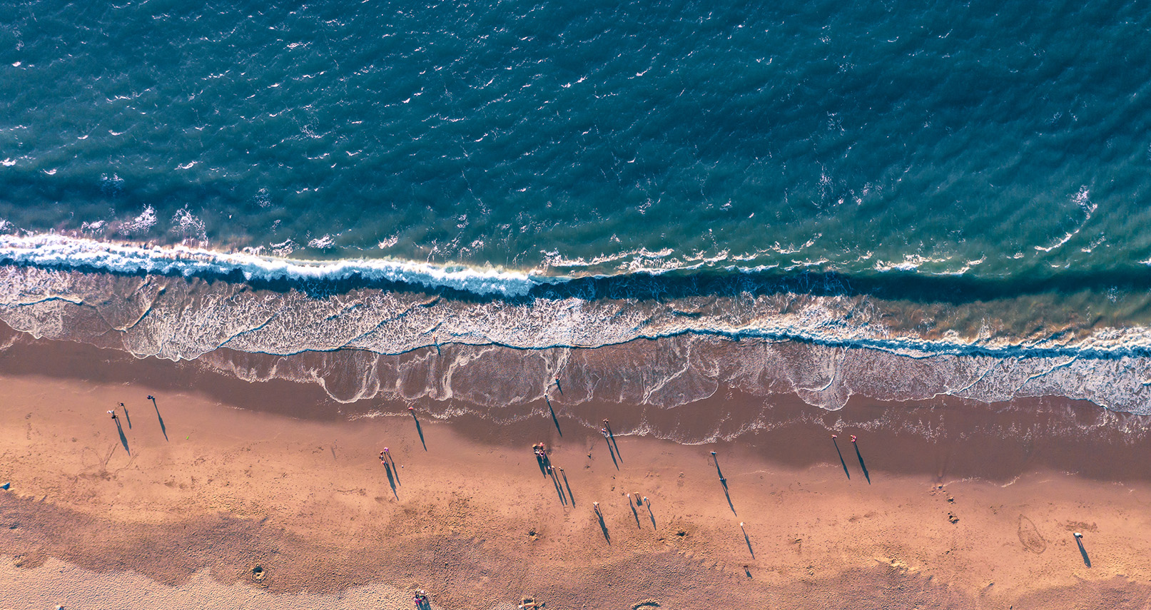 aerial view of a beach with waves coming in and people on the beach.