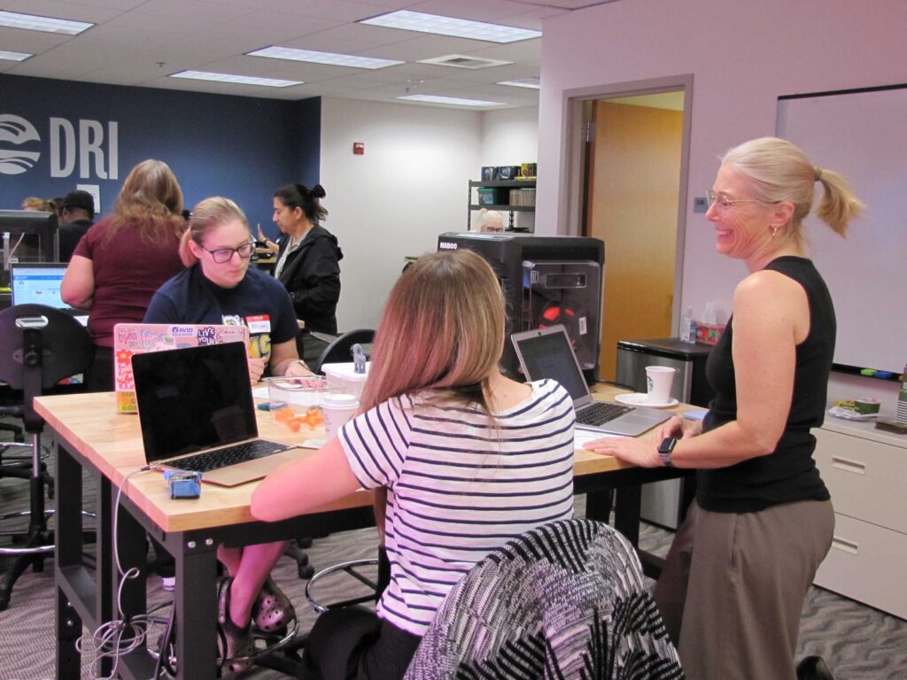 Educators are working at a table with laptops and various STEM tools during a training session in the STEM Co-Lab.