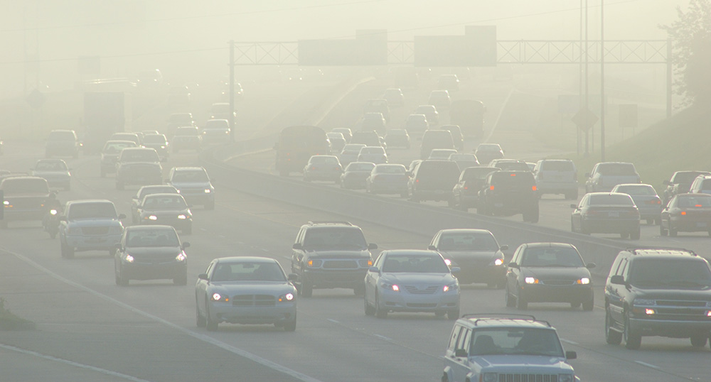 Cars at rush hour on a highway seen through the smog.