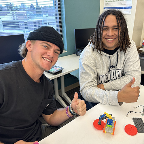 FR-2-men-at-table-thumbs-up Two men at a table building robots smiling with thumbs up.