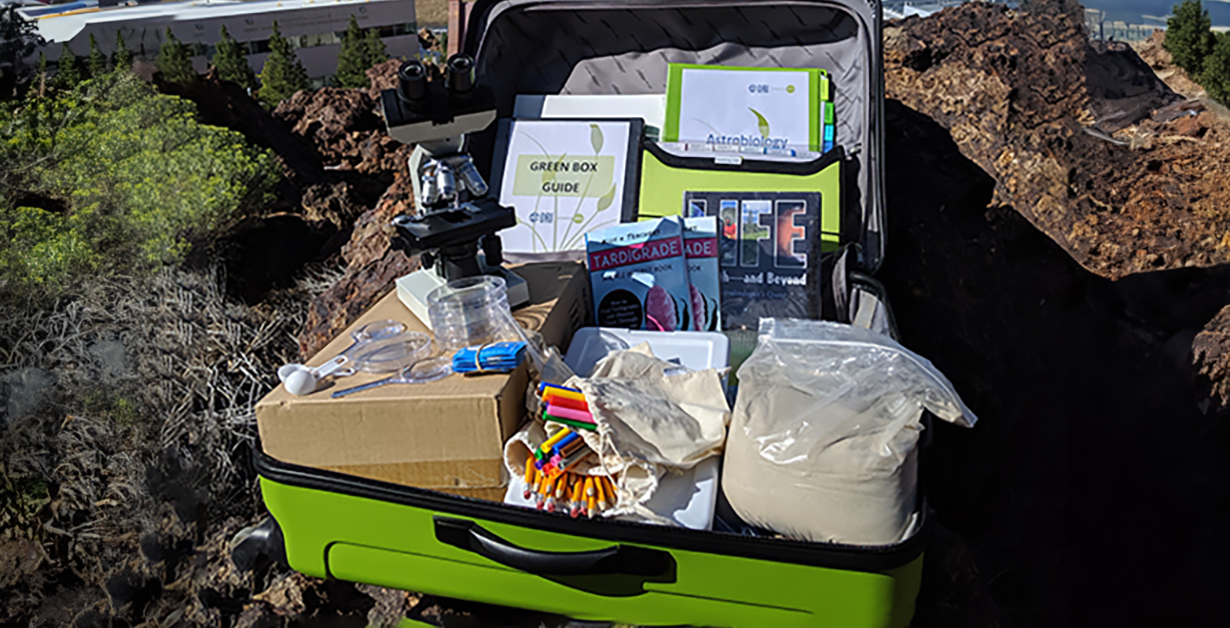 Green suitcase with supplies and binders and handouts for a STEM lesson.