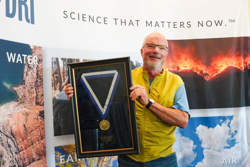 Man in yellow vest holding an award.