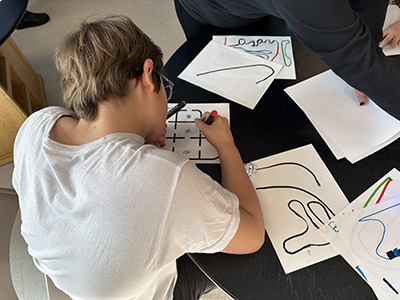IMG_9306-scaled A student drawing a track for a small robot to follow.