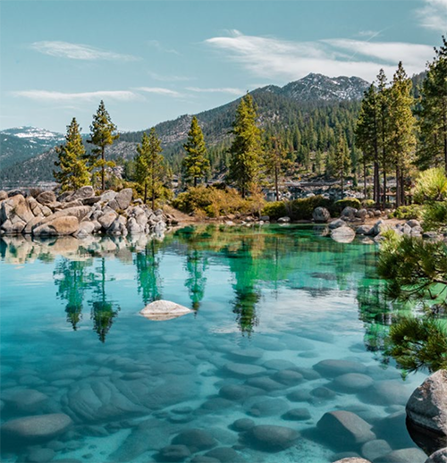 Lake Tahoe Clear blue water of lake tahoe with pine trees and mountains in the distance.