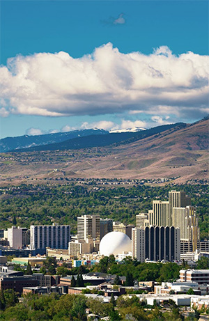 Screenshot Downtown Reno with the sun shining and the mountains and clouds in the distance.