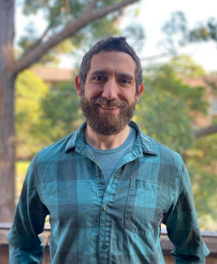 Luke Gliganic photo NEW Photo of Luke Gliganic in blue plaid shirt outside in front of trees.