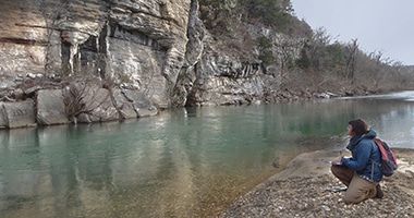 women looks at rock wall along a river