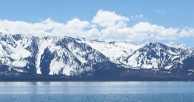 Landscape view of mountains covered in snow next to a lake.