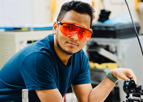 Prakash Gautam in the lab working with equipment and wearing protective eye covering.