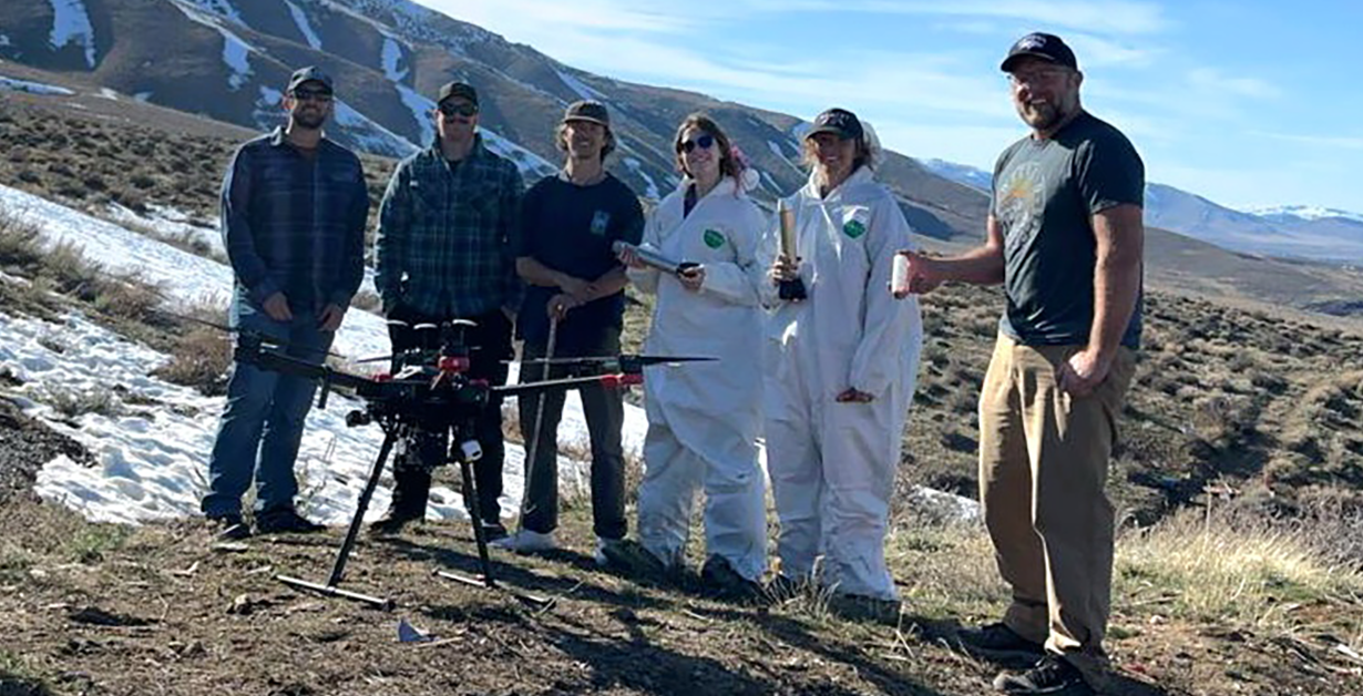 Students and Instructors in front of a drone on the side of the mountain with snow on the ground.