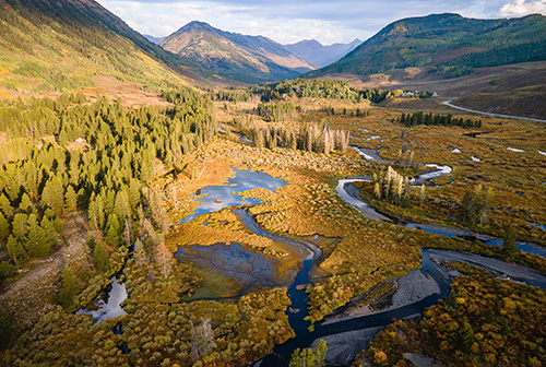 SAR 2025 Vol 1 Landscape overlooking the valley between mountains featuring a river, trees, and marshy areas.