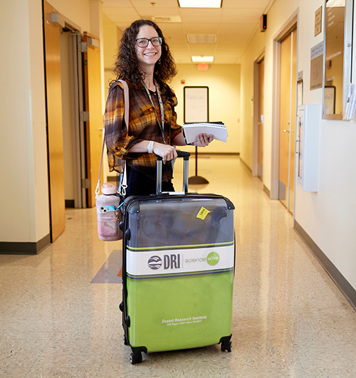 STEM Co-Lab - Green Box Training with Educator An educator smiling in a hallway at DRI with a Green Box suitcase.