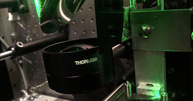 A laser is bounced off of a mirror and through a lens.