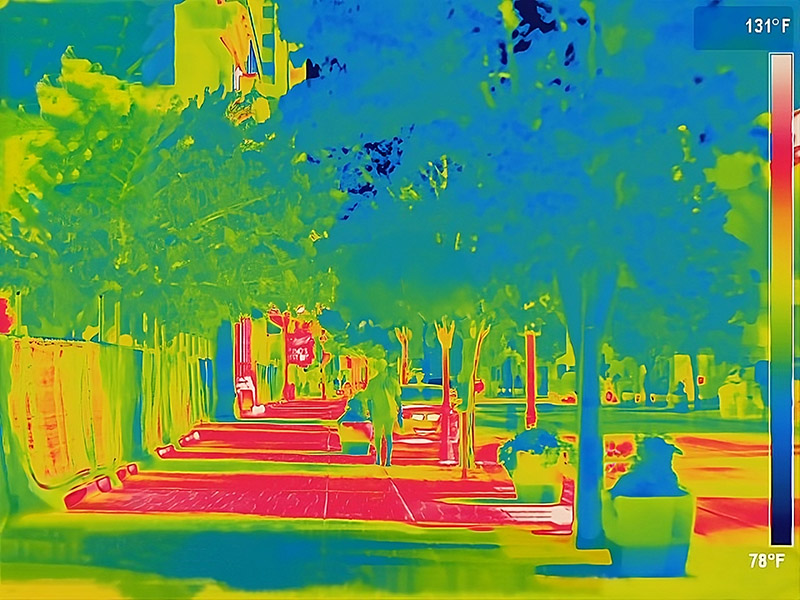 Thermal image of a sidewalk in downtown reno where the areas in red show the areas not shaded by the trees. The shaded areas show up as greens and blues. Temperature range is indicated as 78F - 131F