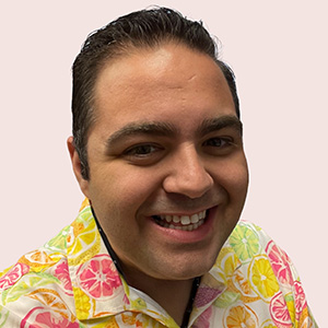 Trevor Headshot 300px Headshot of Trevor smiling and wearing a colorful printed collared shirt.
