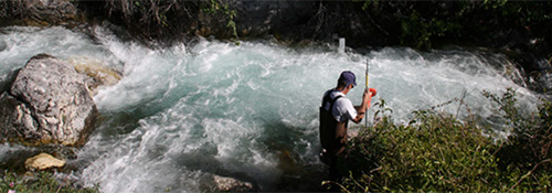 Water Quality Green Box Flow measurement A researchers in a fast moving stream measuring flow.