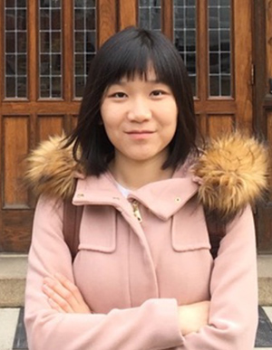 Yi Zhang 300px Headshot of Yi Zhang outside wearing a coat and in front of wooden doors.