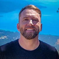 Photo of Zach at an elevation that overlooks a landscape featuring a lake.